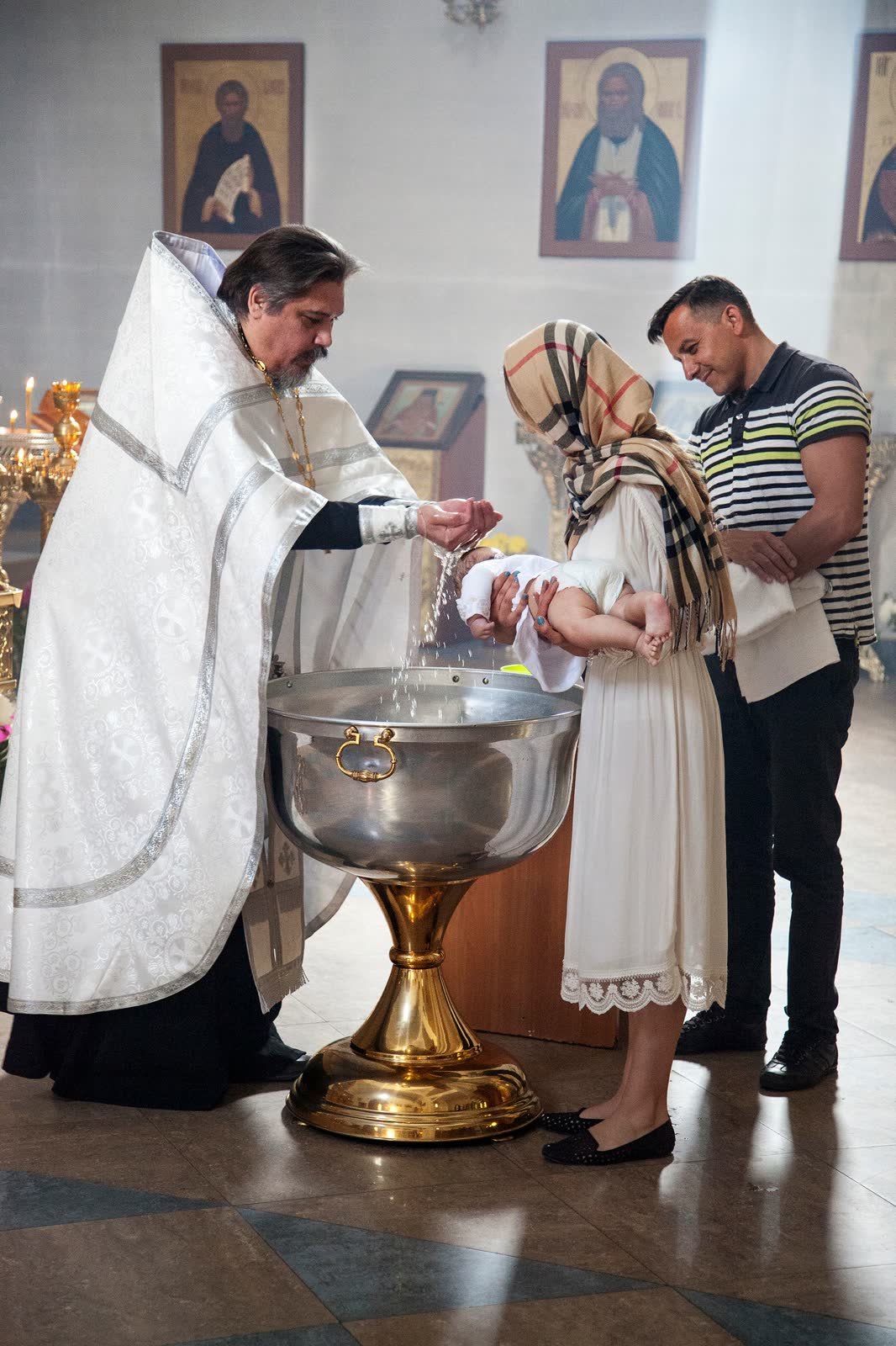 Priest baptizing a baby at the font