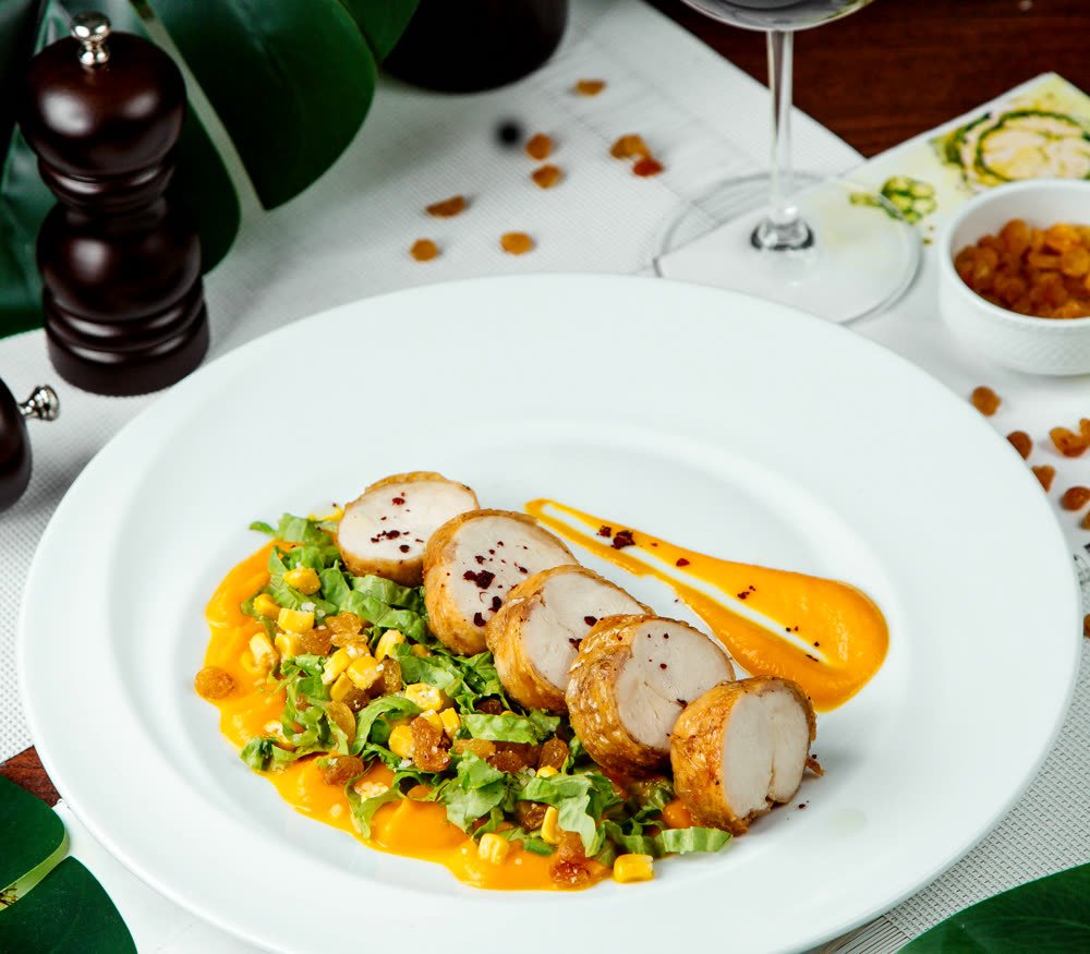 Plated chicken rolls with sauce and a glass of wine