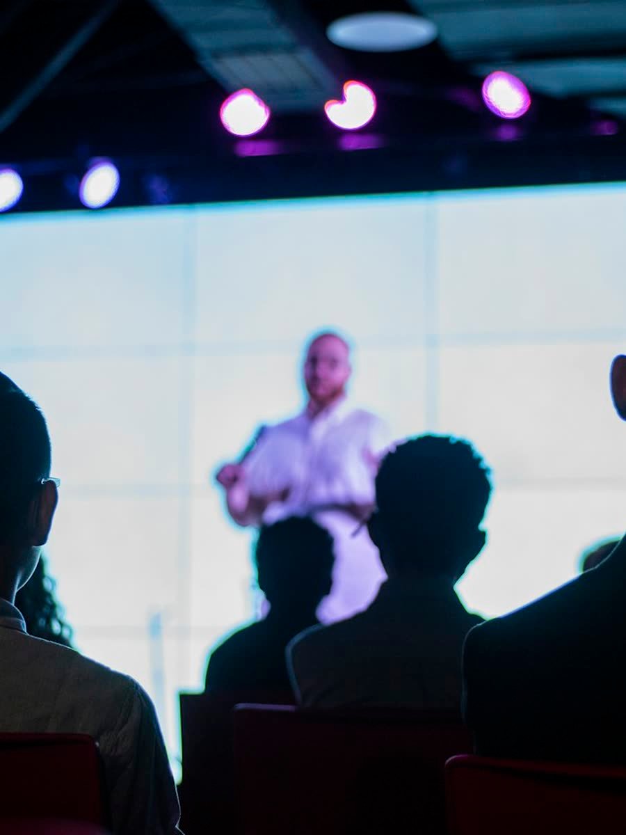 Speaker presenting on stage to a conference audience