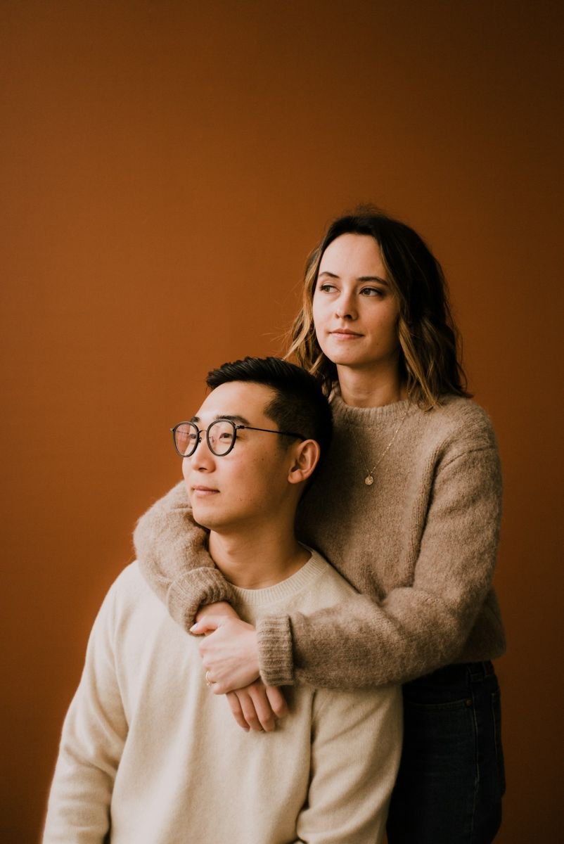 Couple portrait against a warm studio backdrop