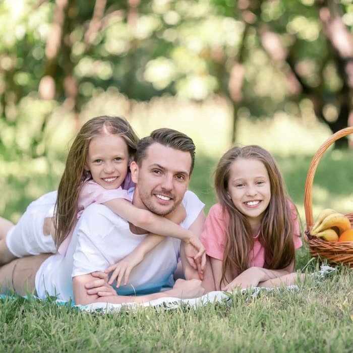 Father and daughters on a picnic blanket