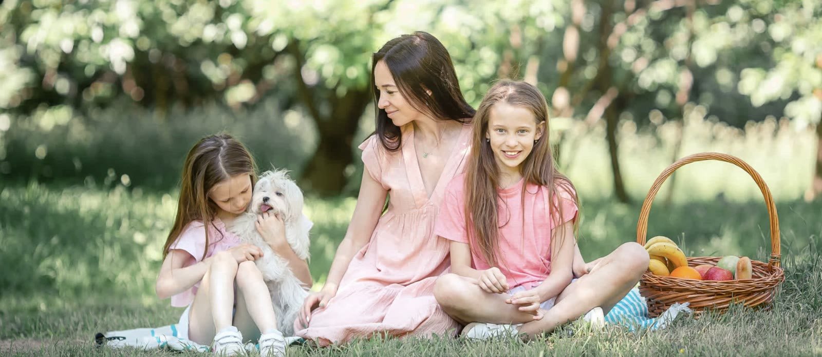 Mother and two daughters with their dog on a picnic in the park