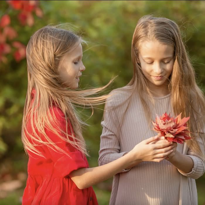 Sisters holding red autumn leaves