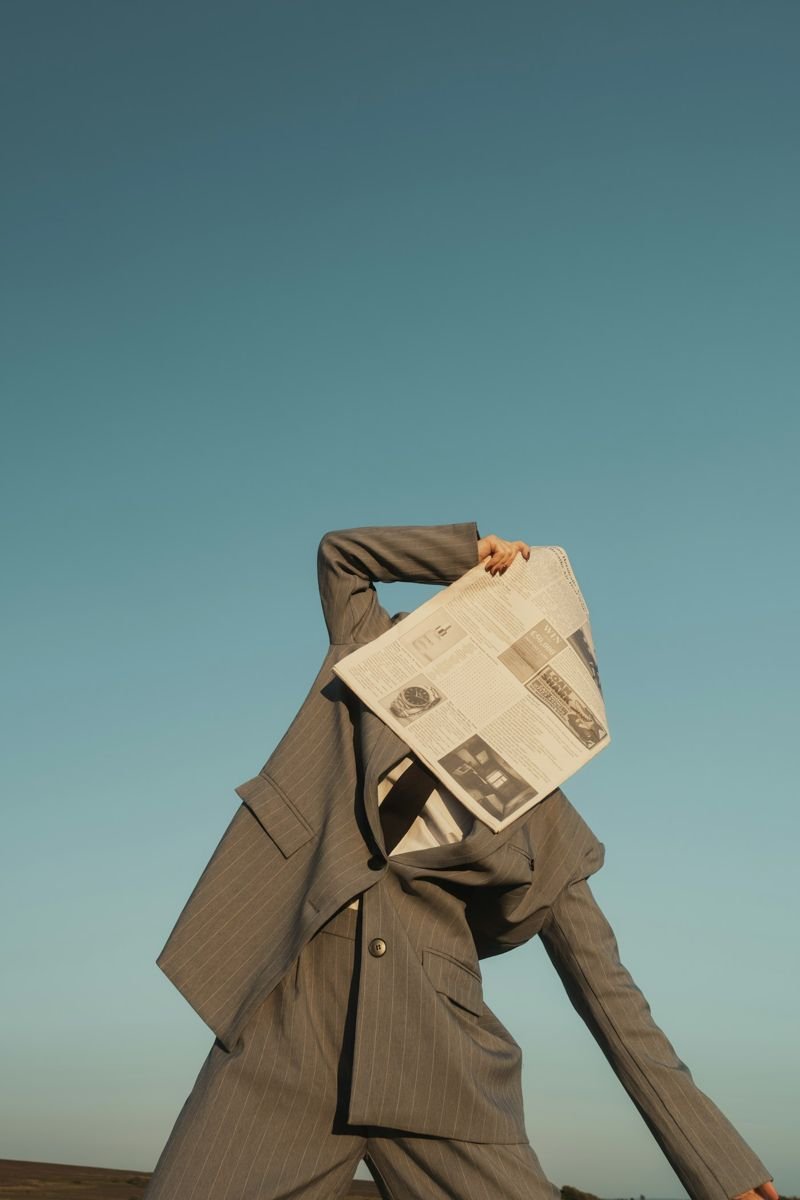 Model in an oversized coat against a teal sky