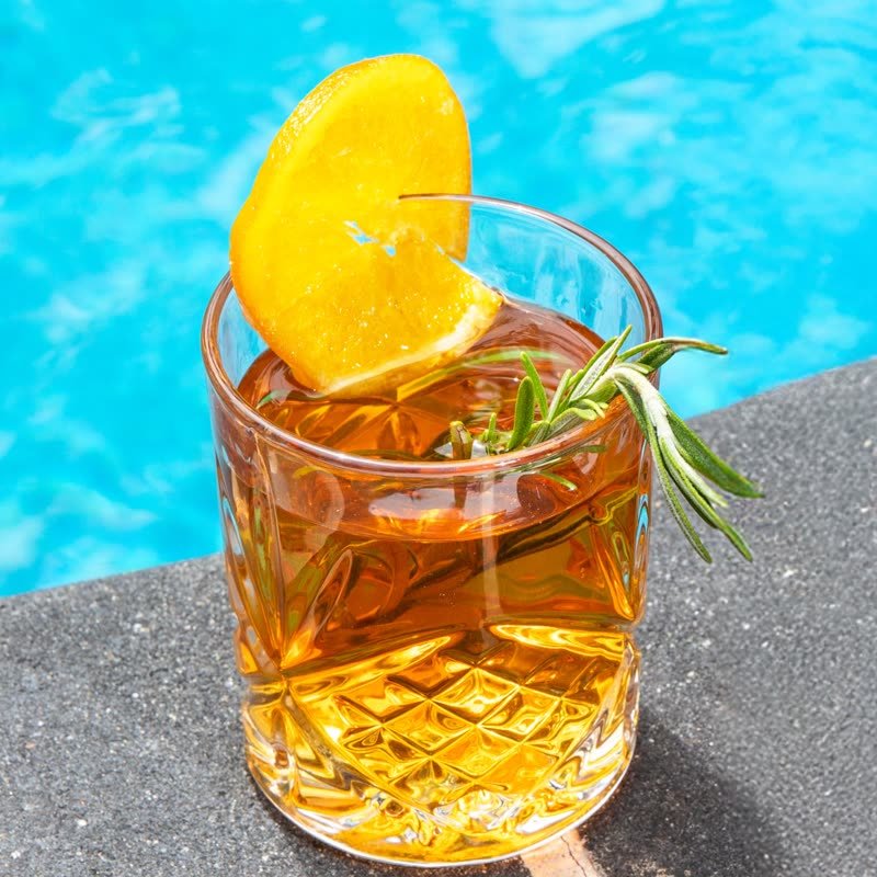 Orange and rosemary drink by a pool