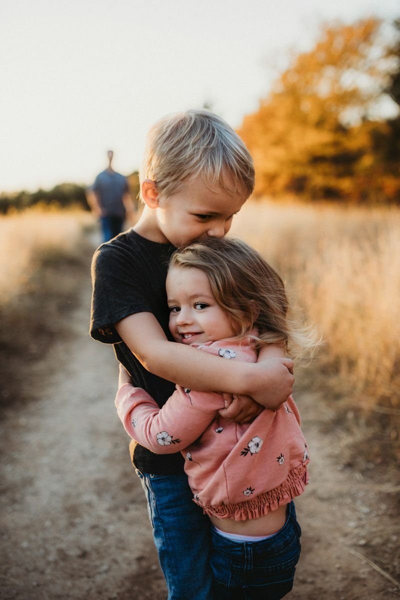Brother hugging his little sister on a country path